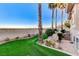 An outdoor oasis with artificial turf, palm trees, rock features, and a view of the surrounding landscape at 1700 Brock Ct, Las Vegas, NV 89117