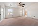 Bright, carpeted bedroom with neutral walls, ceiling fan, two windows, and an ensuite bathroom at 3581 Ranger Way, Pahrump, NV 89048