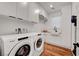 Well-lit laundry room with white cabinets, wooden floors, and modern Whirlpool washer and dryer at 394 Red Feather Peak Ct, Las Vegas, NV 89138