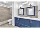 Modern bathroom featuring a double sink vanity with blue cabinets and a tiled shower at 3946 Torsby Pl # 3946, Las Vegas, NV 89119