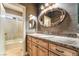 Tastefully designed bathroom featuring a wooden vanity with a granite countertop and a tub shower with decorative tiles at 4014 Trapani Pl, Las Vegas, NV 89141