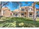 Backyard view of a two-story home featuring a well-maintained lawn, a private balcony, and a tile roof under a clear blue sky at 5305 La Patera Ln, Las Vegas, NV 89149