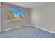 A bright bedroom has neutral walls, plush blue carpeting, and a window with a pleasant view of the community at 5305 La Patera Ln, Las Vegas, NV 89149