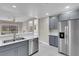 Kitchen with gray cabinets and stainless steel refrigerator, open to living room and fireplace at 5305 La Patera Ln, Las Vegas, NV 89149