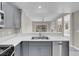 Kitchen with stainless steel appliances, sink, and gray cabinets, open to the carpeted living room at 5305 La Patera Ln, Las Vegas, NV 89149