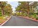 Gated Community entrance with mature trees, lush landscaping, and well maintained asphalt streets at 5305 La Patera Ln, Las Vegas, NV 89149