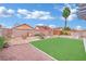 Backyard featuring a manicured synthetic lawn, decorative rock, and mature palm tree at 585 Jackson Dr, Henderson, NV 89014