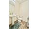 Well-lit bathroom with wood-look flooring, large round mirror, and pedestal sink at 6840 Sunflower Fields St, North Las Vegas, NV 89086