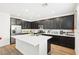 Bright kitchen features an island with quartz countertop, stainless steel appliances and dark cabinetry at 6844 Bayou Hollow Ave, Las Vegas, NV 89156