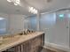 Bathroom featuring a dual sink vanity, a large mirror, and a glass-enclosed shower with tile surround at 8144 Monsoon Bay St, Las Vegas, NV 89113