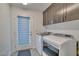 Bright laundry room with modern washer and dryer, gray cabinets and a door with a shade at 8144 Monsoon Bay St, Las Vegas, NV 89113