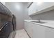 Well-equipped laundry room features modern washer/dryer units and white storage cabinets at 8904 Saint Pierre Dr, Las Vegas, NV 89134