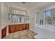 Bright bathroom featuring double sinks, vanity, and a soaking tub by a window at 1009 Rustridge Ave, North Las Vegas, NV 89081