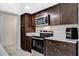 Well-lit kitchen with dark wood cabinets, stainless steel appliances, and white countertops at 1500 Saylor Way, Las Vegas, NV 89108