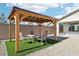 Backyard patio featuring a wooden pergola, a dining table, and low-maintenance turf surrounded by gravel at 2255 Woodbluff Ave, North Las Vegas, NV 89086