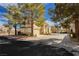 Exterior view of the house with a tile roof, tan siding, a two-car garage, and mature trees in the neighborhood at 2345 Cliffwood Dr, Henderson, NV 89074