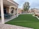 Expansive backyard featuring manicured artificial turf, a covered patio, and beautifully landscaped desert surroundings at 2536 Faiss Dr, Las Vegas, NV 89134