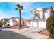 Charming two-story stucco home featuring a two car garage, desert landscaping and a mature palm tree at 4411 Elk Point Cir, Las Vegas, NV 89147