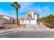 Two-story stucco home with a two-car garage, desert landscaping, mature palm tree and wide driveway at 4411 Elk Point Cir, Las Vegas, NV 89147