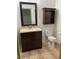 A well-lit half bathroom featuring a charming vanity with a dark wood cabinet and a decorative mirror at 75 N Valle Verde Dr # 621, Henderson, NV 89074