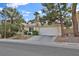 Charming single-story home featuring a well-maintained front yard, a two-car garage, and mature trees at 7713 Shore Haven Dr, Las Vegas, NV 89128