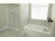 Bathroom featuring a glass enclosed shower, soaking tub, tiled flooring, and modern fixtures at 1617 Meadow Bluffs Ave, Henderson, NV 89014
