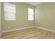 Sunlit bedroom boasts wood-look flooring, neutral walls, and two bright windows with modern blinds at 1617 Meadow Bluffs Ave, Henderson, NV 89014
