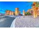 Elegant community entrance with stone archway, lush landscaping, and palm trees under a vibrant blue sky at 20 Via Mantova # 106, Henderson, NV 89011