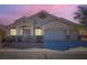 Dusk view of single story home featuring a three-car garage and desert landscaping at 2617 Tanagrine Dr, North Las Vegas, NV 89084