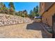 View of the backyard showing stone retaining wall and covered patio area at 264 Crestview Dr, Las Vegas, NV 89124