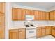 Close-up of the kitchen, featuring a white range and microwave, and wood cabinetry at 473 Elm Crest Pl, Henderson, NV 89012