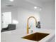 Close up of a kitchen island and gold faucet with white cabinets and quartz countertops at 714 Lacy Ln, Las Vegas, NV 89107