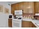 Charming kitchen with white appliances, wood cabinets, brick backsplash and ample counter space at 7274 Pinebrook Cir, Las Vegas, NV 89147