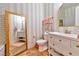 Bright bathroom featuring striped walls, vanity with storage, and decorative mirror at 7565 N Torrey Pines Dr # A, Las Vegas, NV 89131