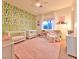 Bedroom with cactus-themed wallpaper, two cribs, and a cozy chair at 7565 N Torrey Pines Dr # A, Las Vegas, NV 89131