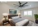 Digitally staged main bedroom with large bed, ceiling fan, and view to the outdoor landscaping at 9741 Panorama Cliff Dr, Las Vegas, NV 89134