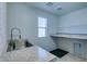 Bright laundry room with stainless steel sink, granite counters, window, and shelving at 981 Soaring Moon Dr, Henderson, NV 89015