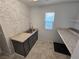 Laundry room featuring gray cabinets, granite counters, stainless sink and brick accent wall at 981 Soaring Moon Dr, Henderson, NV 89015