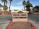 Pecos Creek Condominiums' sign surrounded by lush palm trees under a partly cloudy sky at 1830 N Pecos Rd # 230, Las Vegas, NV 89115