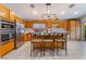 Bright kitchen features stainless appliances, wooden cabinets, island with bar seating, and unique light fixture at 1835 Swallow Hill Ave, Henderson, NV 89012