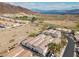 Scenic aerial view of a desert community with tile-roofed homes near a lake and mountains under a partly cloudy sky at 262 Big Horn Dr, Boulder City, NV 89005