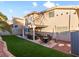 A backyard featuring a covered patio with a dining area, artificial grass, brick accents, and privacy wall at 5505 Big Sky Ln, Las Vegas, NV 89149