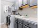 Bright laundry room with gray cabinets, tile counters, stainless steel sink, and front loading washer and dryer at 5505 Big Sky Ln, Las Vegas, NV 89149