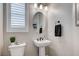 Stylish powder room featuring a pedestal sink, oval mirror, and modern fixtures, creating an elegant and functional space at 690 Monroe Hill Pl, Henderson, NV 89011