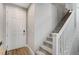 Bright entryway showcasing a white front door, wood-look tile flooring, and carpeted stairs with white railings at 690 Monroe Hill Pl, Henderson, NV 89011