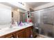 Bathroom with a shower with sliding glass doors and double sinks with a wood-look vanity at 9293 Boltonia Ct, Las Vegas, NV 89149