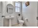 Well lit half bathroom featuring a white pedestal sink, toilet, and framed artwork at 933 Monte Nerone Ave, Henderson, NV 89012