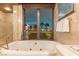 Bright bathroom featuring a soaking tub, marble finishes, and a large window with a city view at 1 Hughes Center Dr # 308, Las Vegas, NV 89169