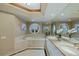 Bright bathroom featuring a large tub, round window, and double sink vanity at 2747 Paradise Rd # 404, Las Vegas, NV 89109