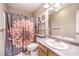 Cozy bathroom with floral shower curtain, shelving, and granite-look countertop at 3192 Taylor St, Logandale, NV 89021